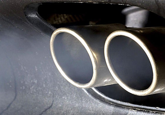 Humo procedente de la combustión de un motor de un coche sale de dos tubos de escape.