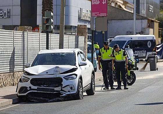 Dos agentes de la Policía Local observan el vehículo del conductor ebrio que atropelló mortalmente a una mujer el miércoles en la carretera de Alicante.
