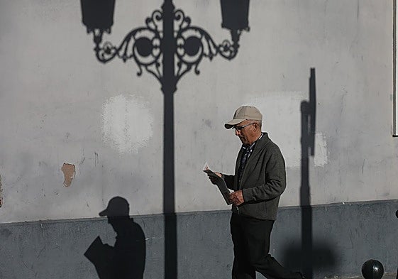 Hombre jubilado pasea por la calle con periódico en mano.