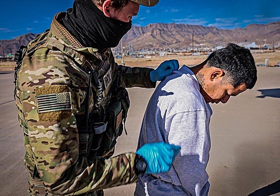 Un agente lleva a un migrante esposado en la base de Guantánamo.