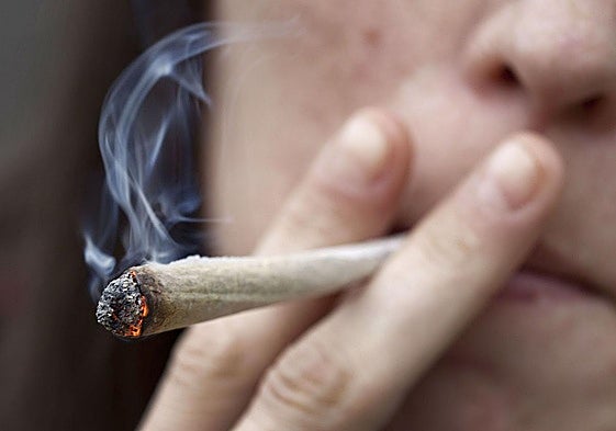 Una joven da una calada a un porro.