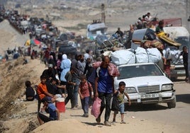 Decenas de palestinos de Ciudad de Gaza se desplazan hacia el sur con sus pertenencias por una carretera.