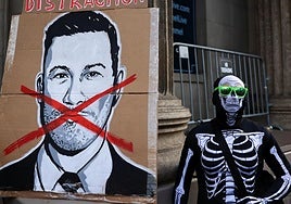 Un manifestante vestido con un traje de esqueleto junto a un cartel de Jimmy Kimmel durante una protesta por el despido del presentador.