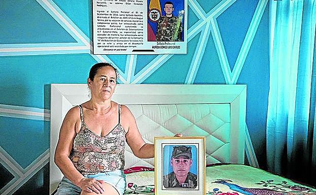 Doris posa con el retrato de su hermano militar muerto. Al fondo, el obituario de su hijo.
