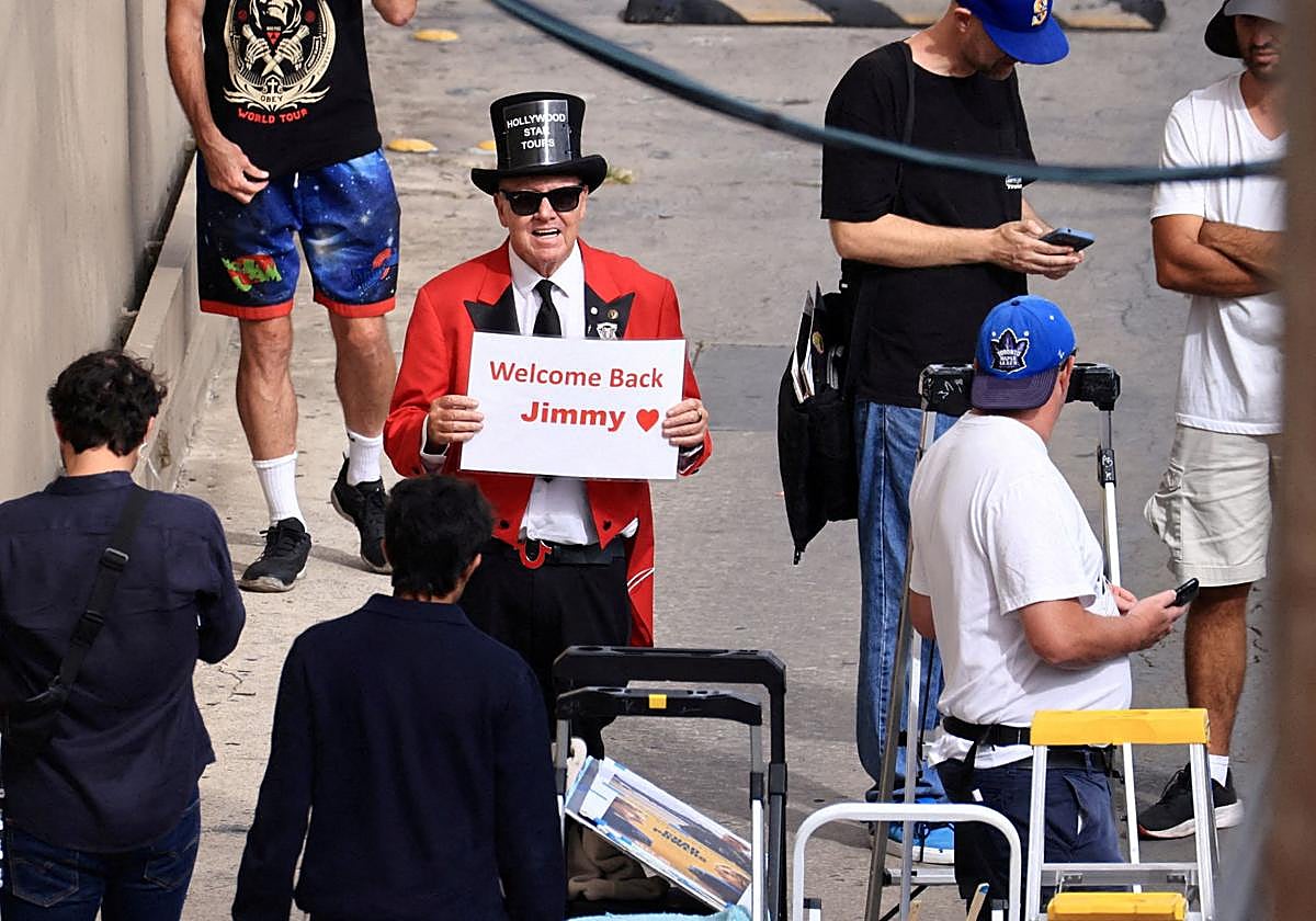 Gregg Donavan sostiene un cartel que dice «Bienvenido de nuevo, Jimmy» fuera del teatro donde se graba su programa.