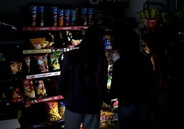 Varios clientes iluminan con el móvil en un supermercado de Barcelona el día del apagón.
