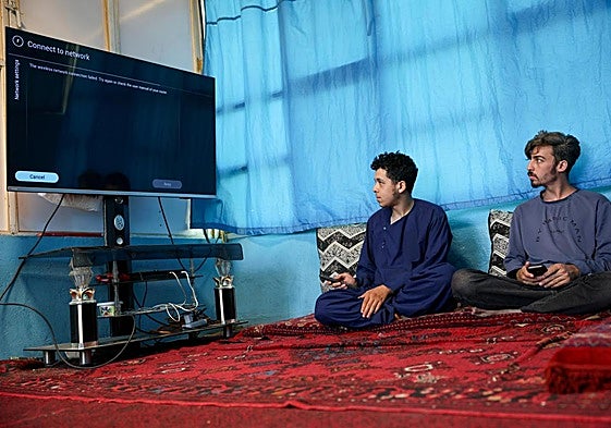 Dos hombres tratan de conectar sin éxito en Kabul su televisor a internet.