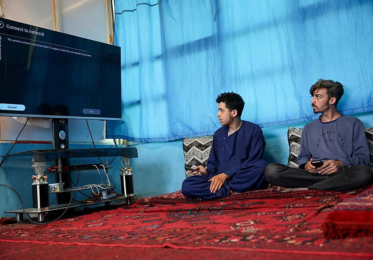 Dos hombres tratan de conectar sin éxito en Kabul su televisor a internet.
