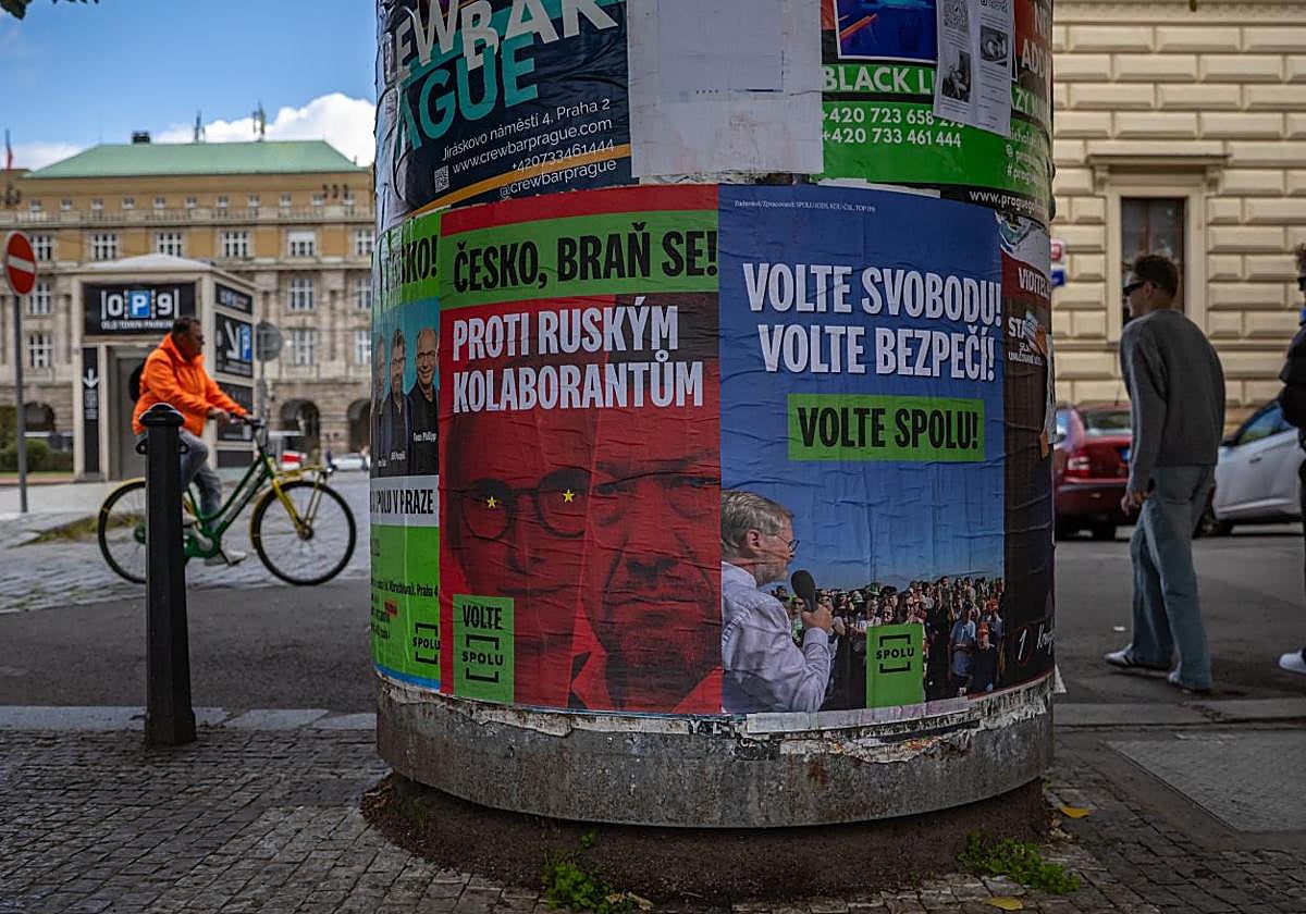 Personas pasan junto a carteles electorales en una calle de Praga.