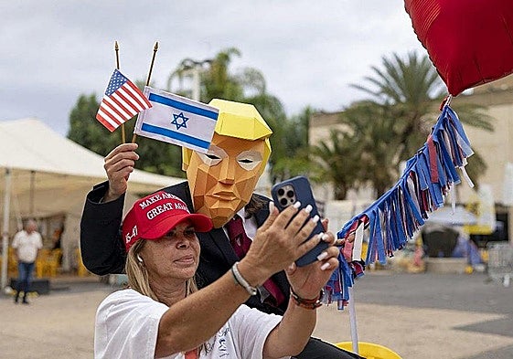 Una mujer israelí se hace una foto con un hombre disfrazado de Donald Trump en Tel Aviv para festejar el acuerdo.