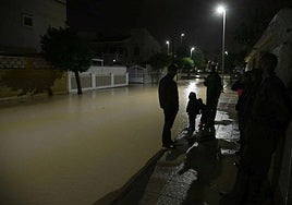 Vecinos de Los Alcázares, de madrugada, en una calle inundada.