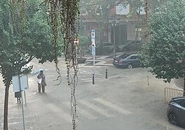 Una mujer intenta cruzar la carretera en una calle inundada de Gandia.