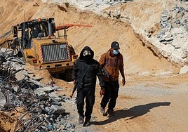 Dos miembros de Hamás, delante de una excavadora en Gaza.