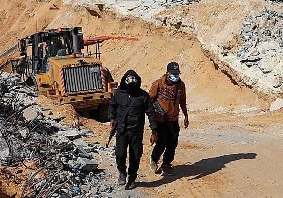 Dos miembros de Hamás, delante de una excavadora en Gaza.