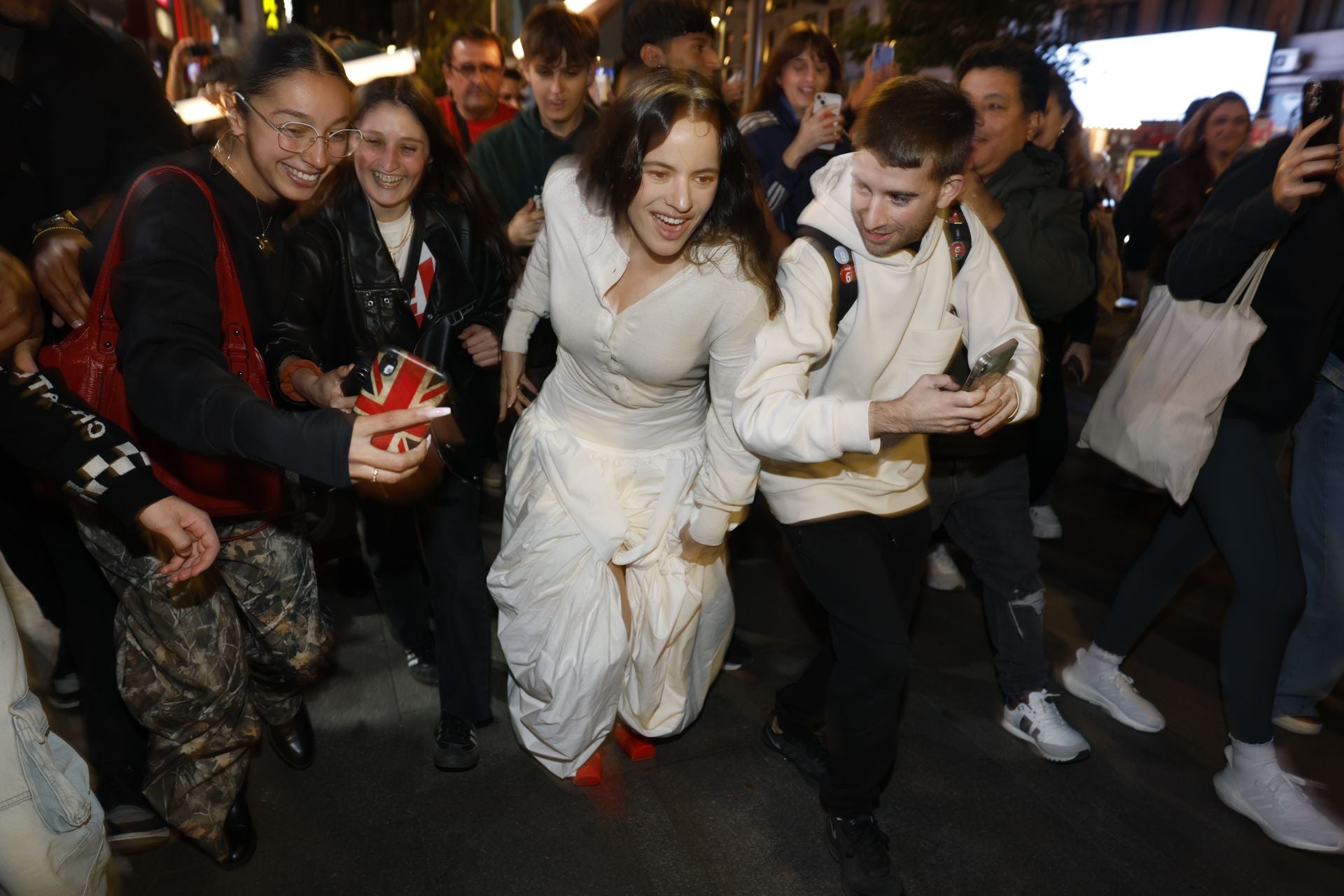 Imagen principal - En las dos primeras imágenes, Rosalía llegando a la plaza de Callao y haciéndose un selfi con varias fans; en la última, cartel promocional de 'Lux', su nuevo disco.