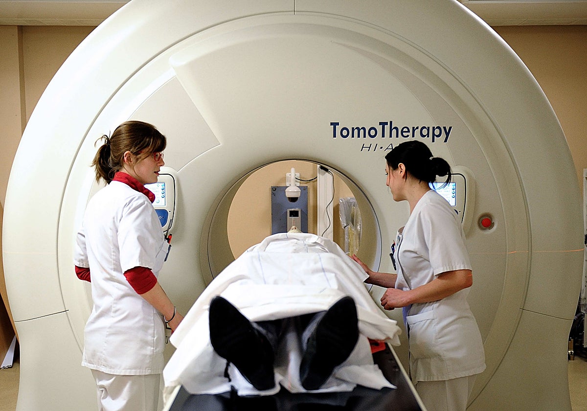 Two healthcare professionals prepare a patient for an MRI scan.