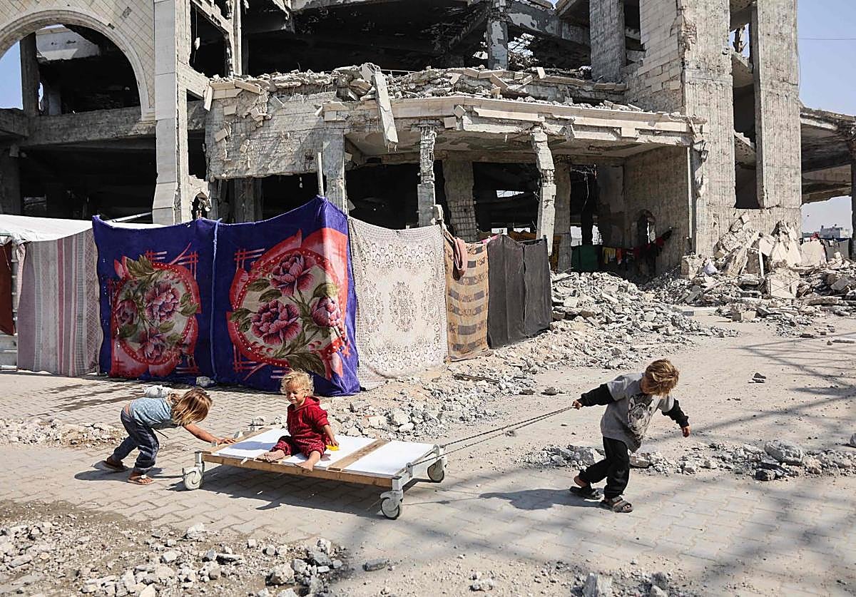 Tres niños juegan en las ruinas de Gaza City.