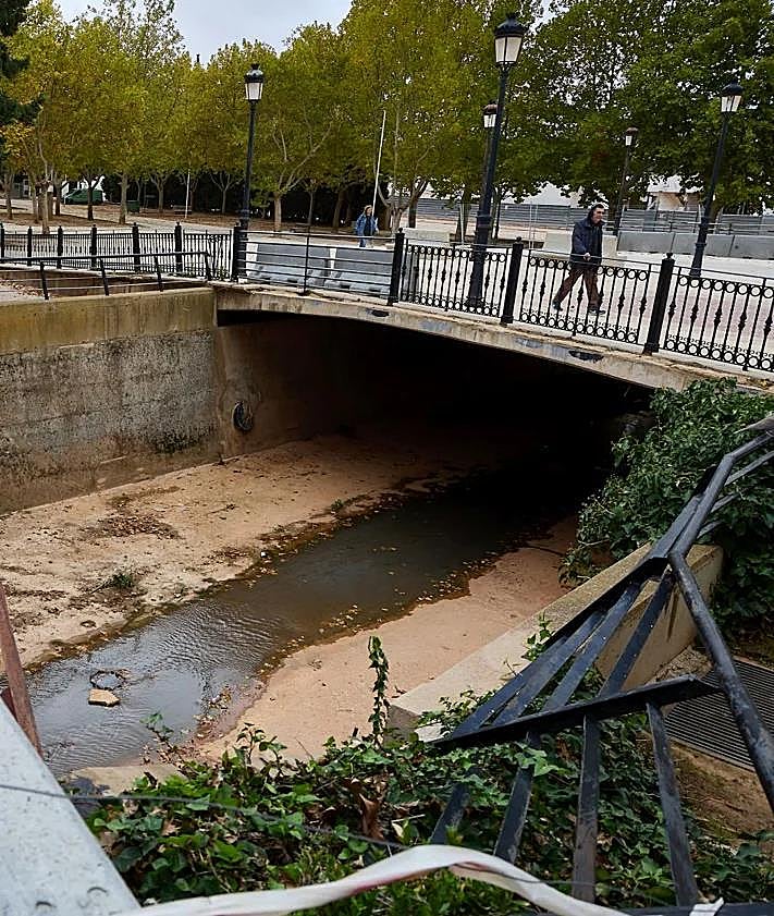 Imagen secundaria 2 - Pedro señala la altura a la que llegó el agua en el interior de su vivienda. David refuerza el pórtico del garaje de una casa. Destrozos en el cauce del Magro todavía sin reparar.