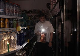 Una persona utiliza su teléfono móvil como linterna en un ultramarinos en Valencia el día del apagón.