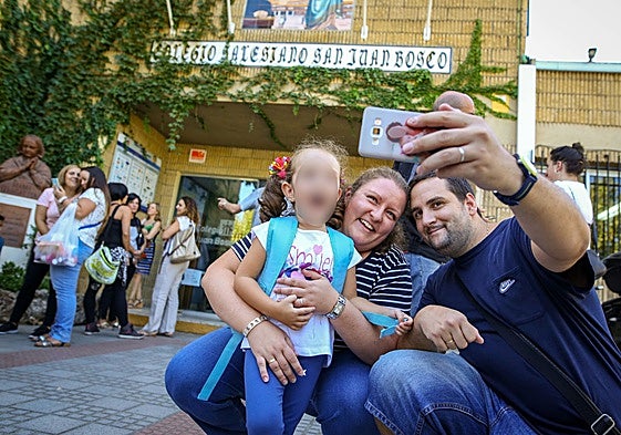Unos padres se hacen un sefi con su hija en la puerta del colegio.