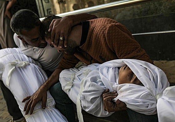 Un hombre sostiene los cuerpos de sus dos hijos en el campo de refugiados de Al Shatea en Gaza tras un ataque israelí.