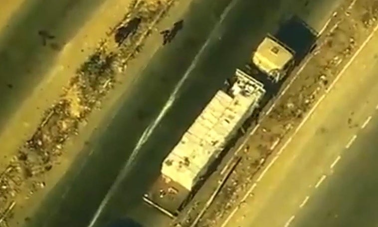 Un miliciano vestido de negro se dirige al camión mientras otros dos dejan al conductor tendido en la mediana de la carretera cerca de Khan Younis.