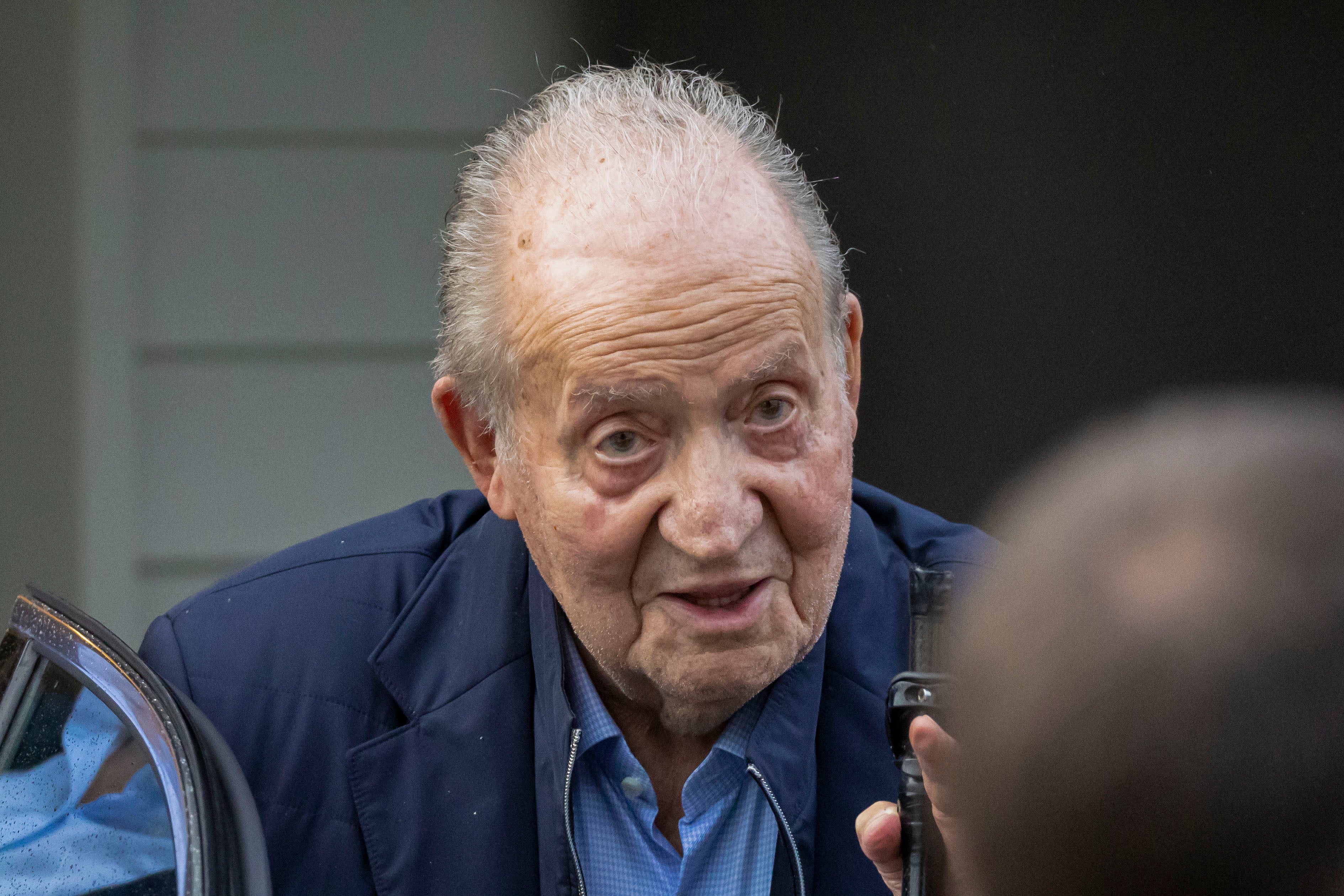 El rey emérito saluda ayer desde un coche tras aterrizar en el aeropuerto vigués de Peinador.