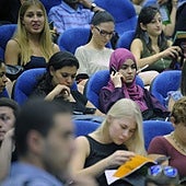 Estudiantes universitarios siguen una presentación en un salón de actos.
