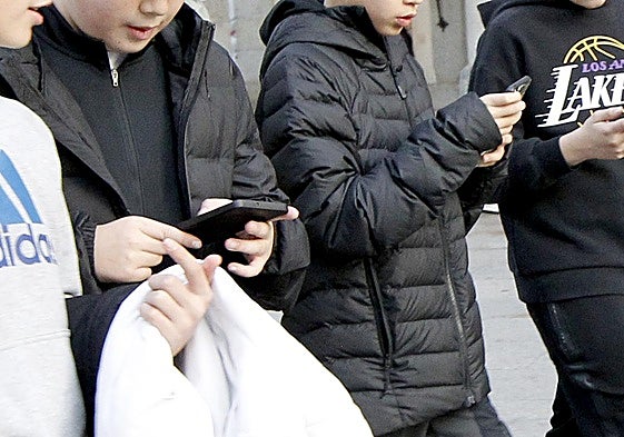 Jóvenes pasean con sus teléfonos móviles.