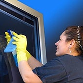 Una empleada de hogar, limpiando un cristal.