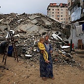 Una mujer sostiene a un niño en una calle en ruinas de Gaza City.
