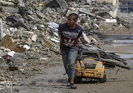 Un chico arrastra un carro con trozos de metal por una calle arrasada por los bombardeos en Ciudad de Gaza.