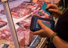 Una señora paga su compra en el Mercado de la Mercé en Barcelona.
