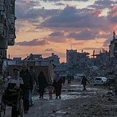 Familias palestinas caminan por un barrio de Gaza City destrozado por los bombardeos de Irsael.