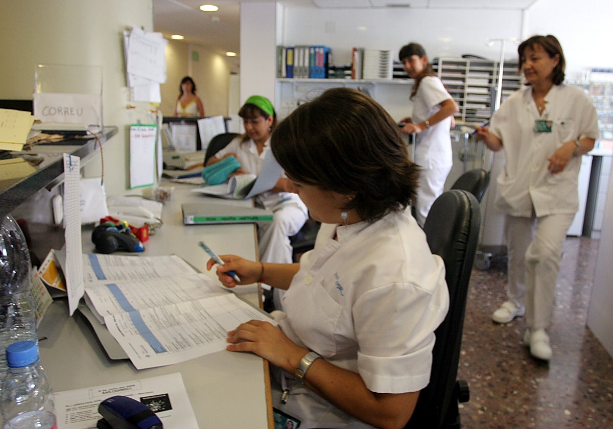 A group of nurses organizing work at a hospital ward control station.