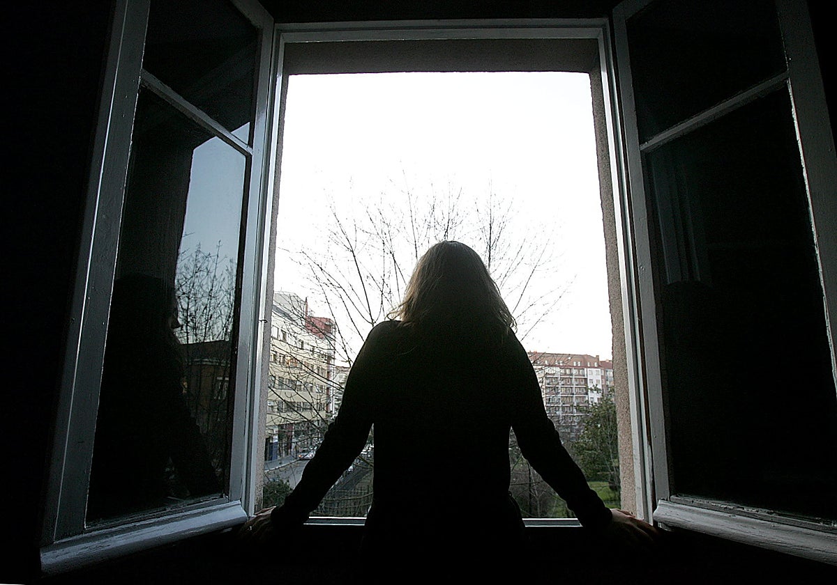 A young woman looks out the window of her room.