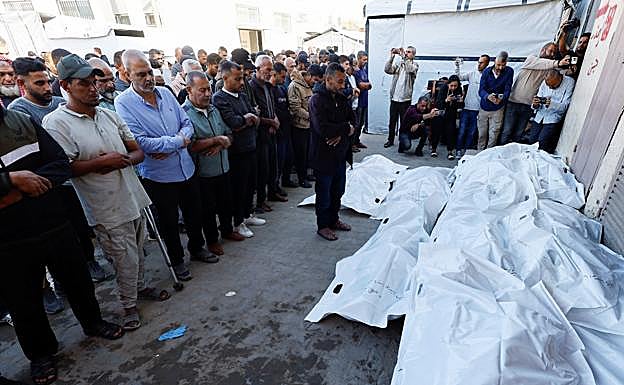 Gazatíes rezan frente a las últimas víctimas mortales.