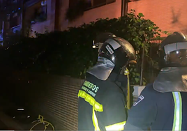 Dos bomberos frente a la vivienda incendiada