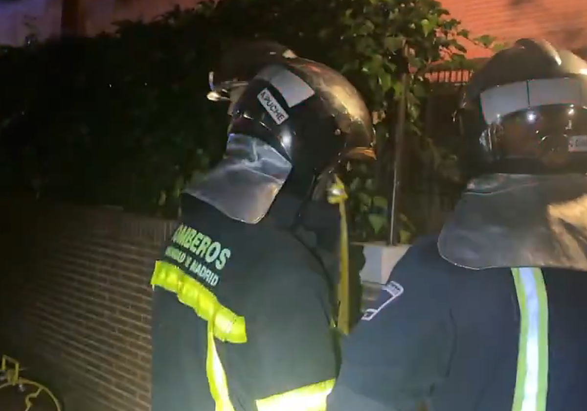 Dos bomberos frente a la vivienda incendiada
