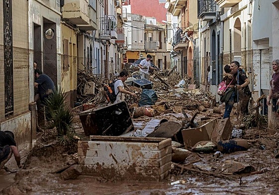 Vecinos intentan atravesar una calle en Paiporta, el pasado octubre de 2024 tras la devastadora dana.