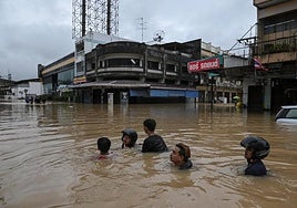 Residentes locales caminan por una zona inundada de la localidad de Hat Yai, en el sure de Tailandia.