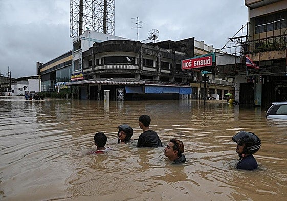 Residentes locales caminan por una zona inundada de la localidad de Hat Yai, en el sure de Tailandia.