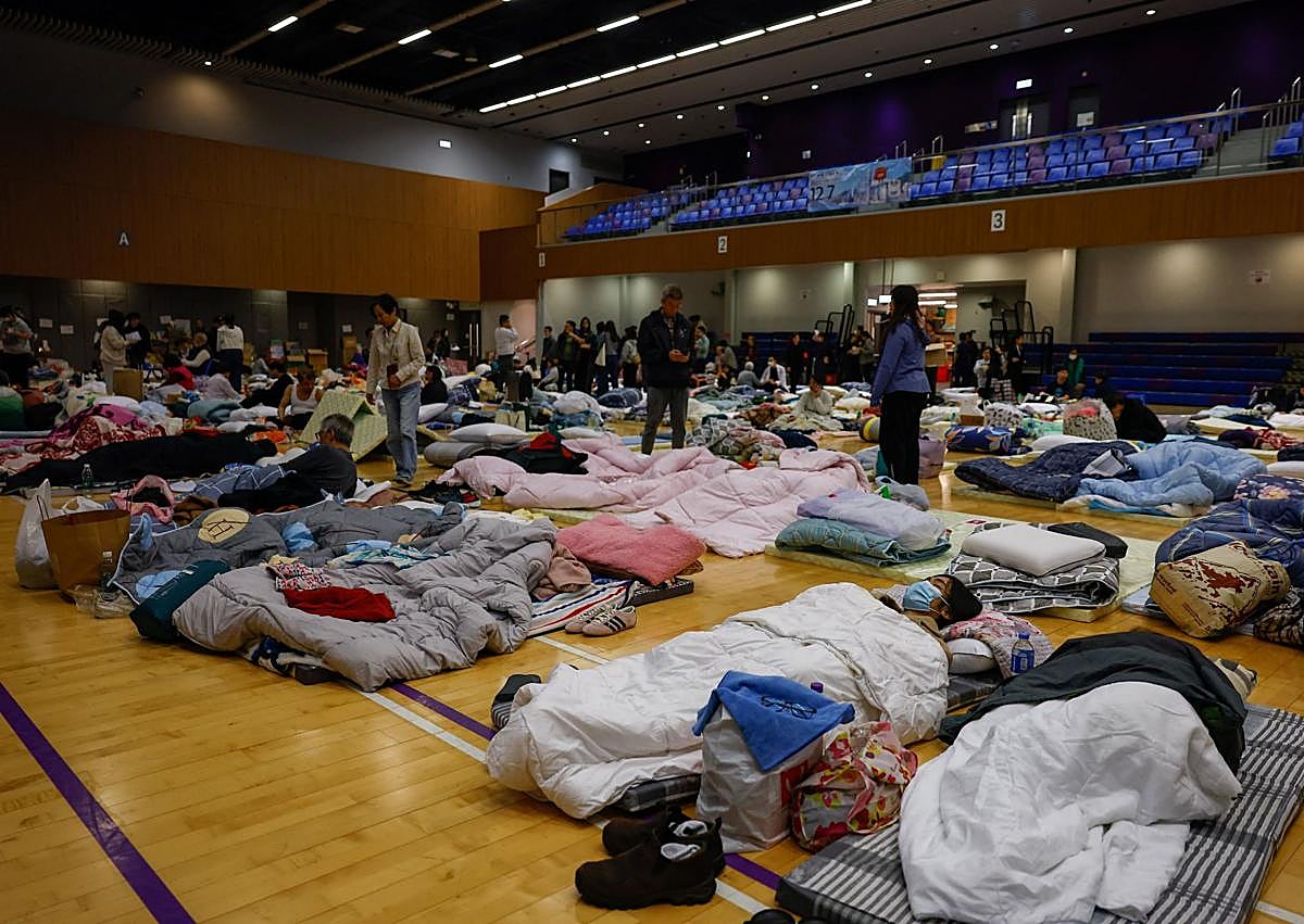 Imagen secundaria 1 - Bomberos trabajan en la zona del incendio; uno de los refugios habilitados para los damnificados; el fuego permaneció activo durante horas.