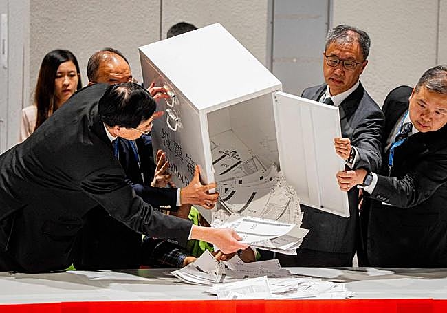 El secretario de Asuntos Constitucionales y Continentales, Erick Tsang Kwok-wai, ayuda a vaciar una urna.