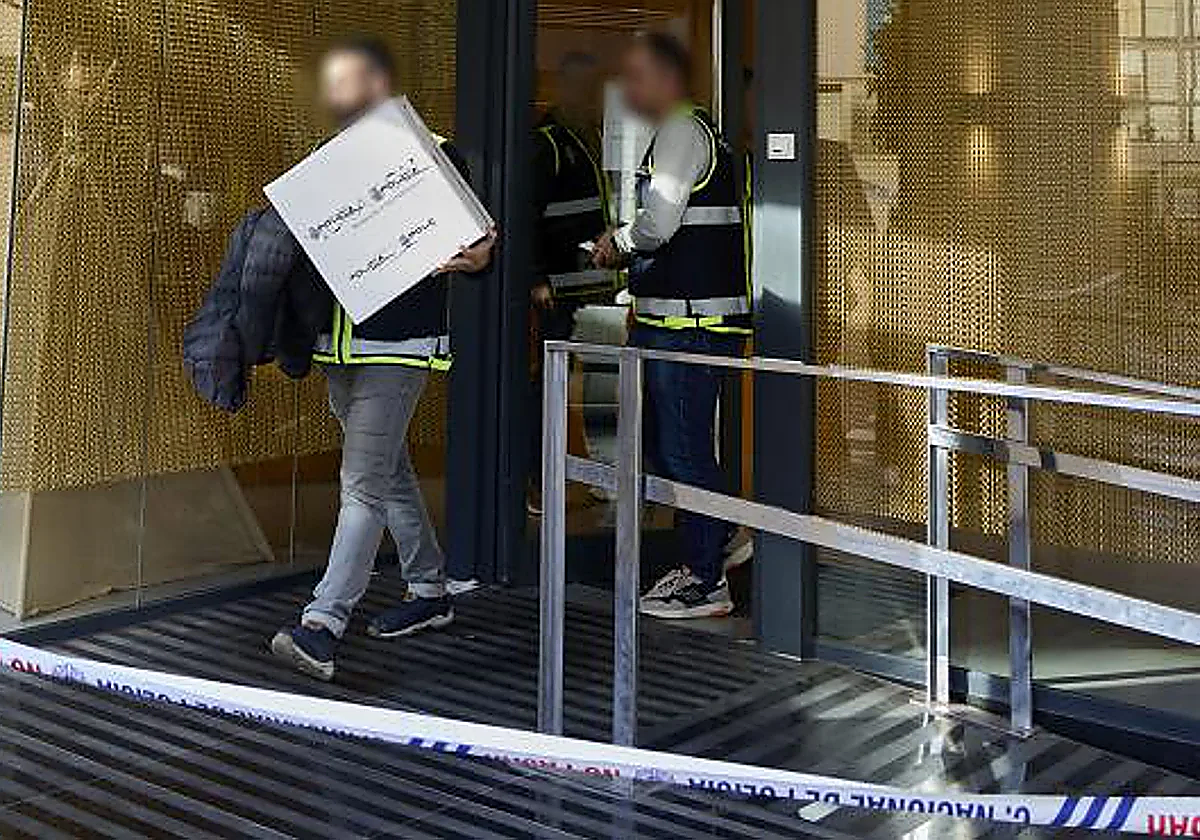 Dos policías, uno de ellos con una caja, salen de la clínica dental de Alzira.