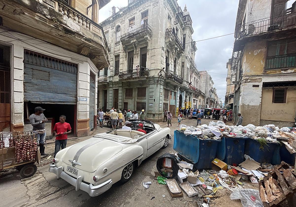 Un automóvil para turistas circula sin clientes por el centro de La Habana, lleno de basura.