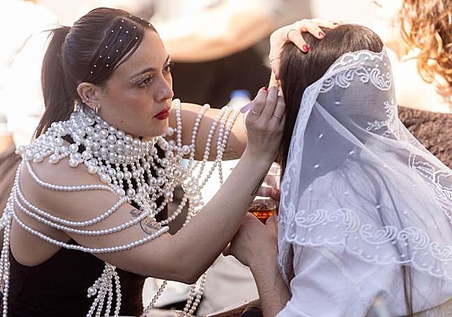 Una fan maquilla a otra mientras hacen cola.