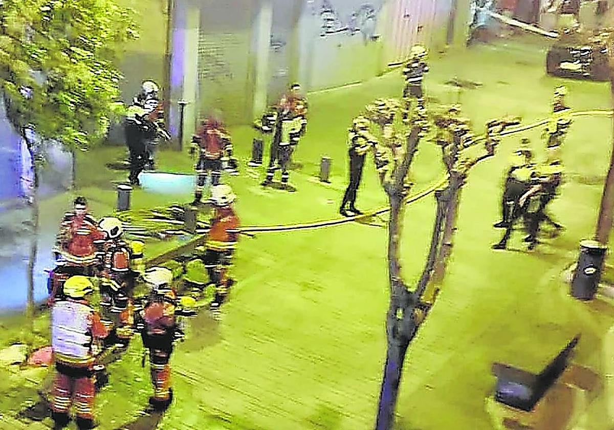 Bomberos y policías locales, tras sofocar el incendio y rescatar a la víctima en Ollerías Altas.