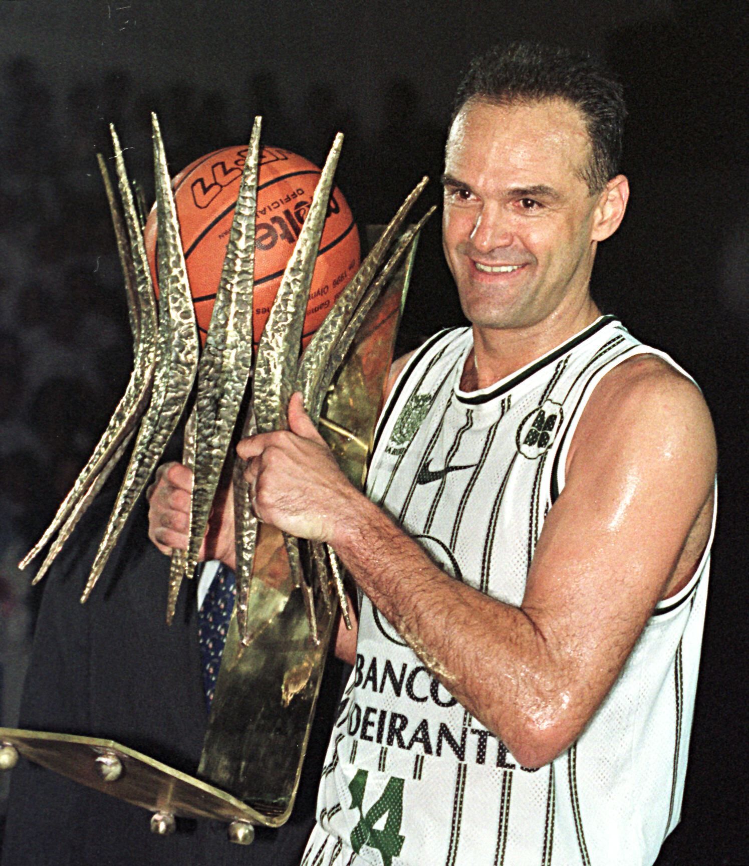 İkincil Resim 2 - Yukarıda, Oscar Schmidt, 1991'deki bir konferans öncesinde NBA yıldızı Earvin 'Magic' Johnson ile şakalaşıyor; Aşağıda Brezilyalı yıldız, 2012 Basketbol Dünya Kupası'nı sunmak üzere Madrid'de düzenlenen bir etkinlik sırasında ve son olarak profesyonel oyuncu olarak geçirdiği 22 başarılı yılın ardından 1998'de aldığı kupayla görülüyor.