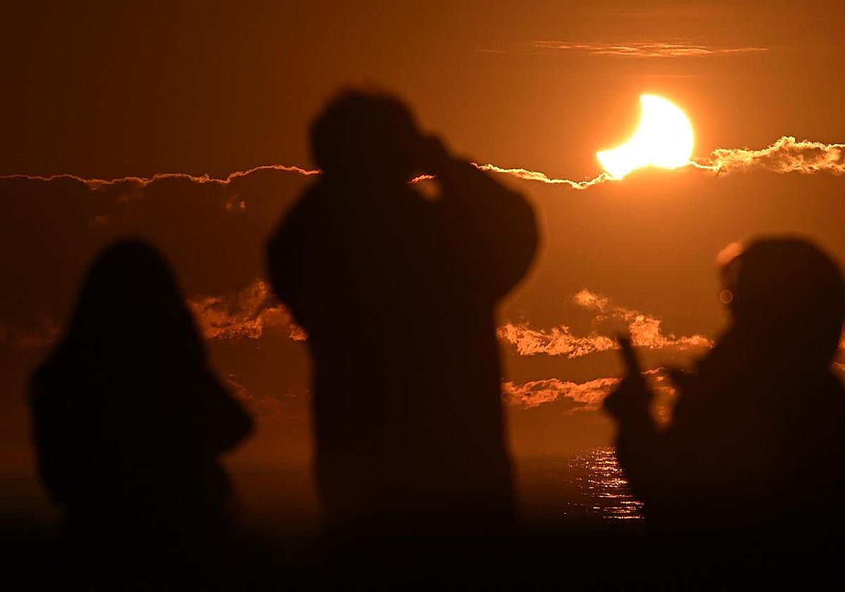 Personas observan un eclipse parcial.